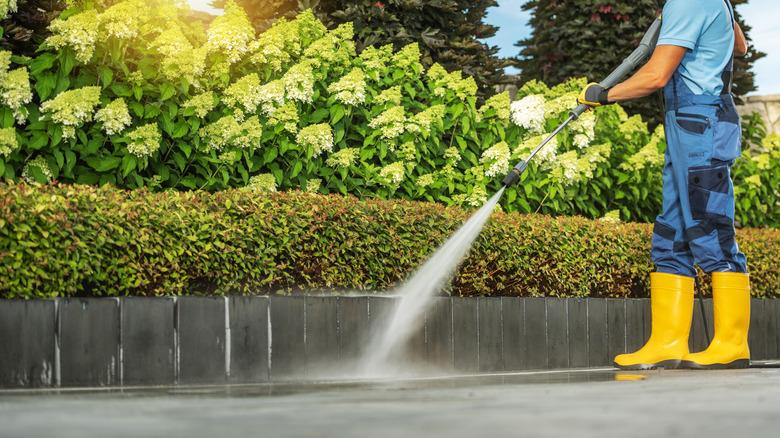 Man pressure washing a concrete driveway
