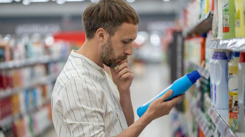 A man inspecting a cleaning product bottle