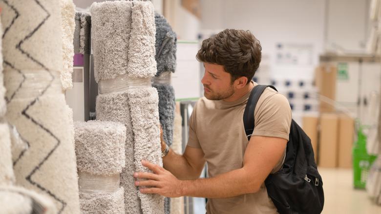 Man looking at rolled-up rugs in store