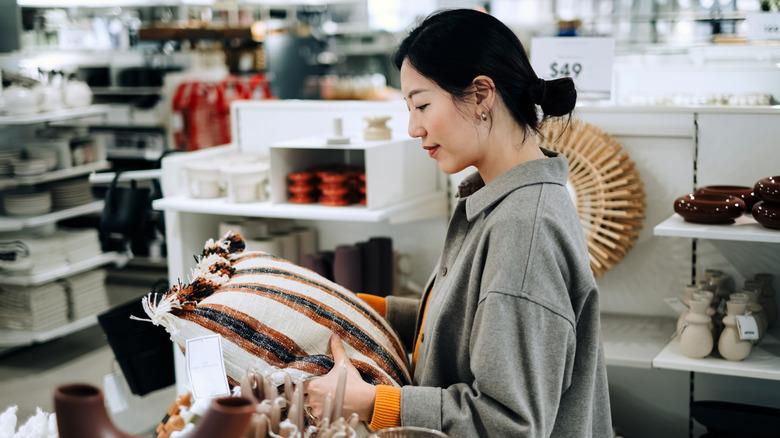 Woman holding a decorative pillow in a store