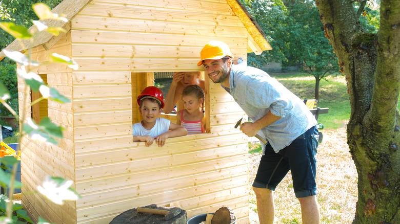 Parent building a playhouse for his children