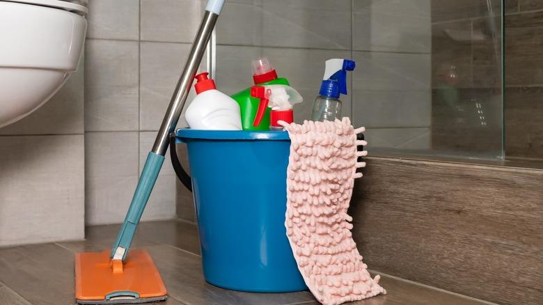 A bucket with cleaning supplies next to shower