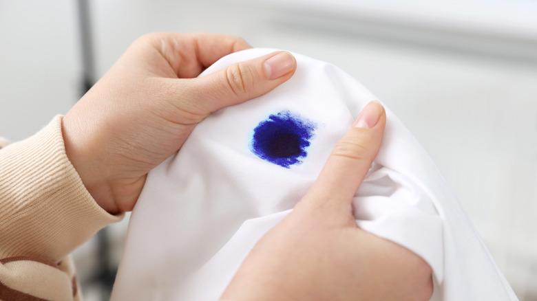 close up of hands holding fabric with blue ink stain