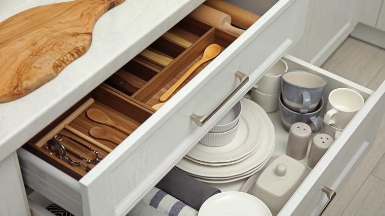 open kitchen drawers with utensils, plates, cups, other kitchen items