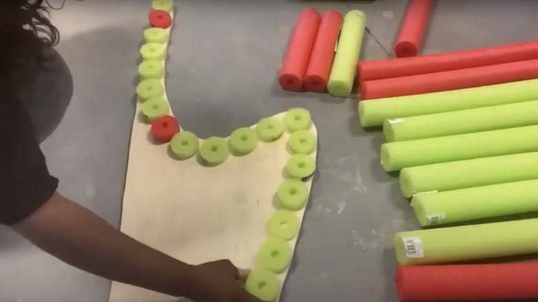lining up pool noodle discs on the plywood side panel of the chair to plan the pool noodle location and layout for the chair