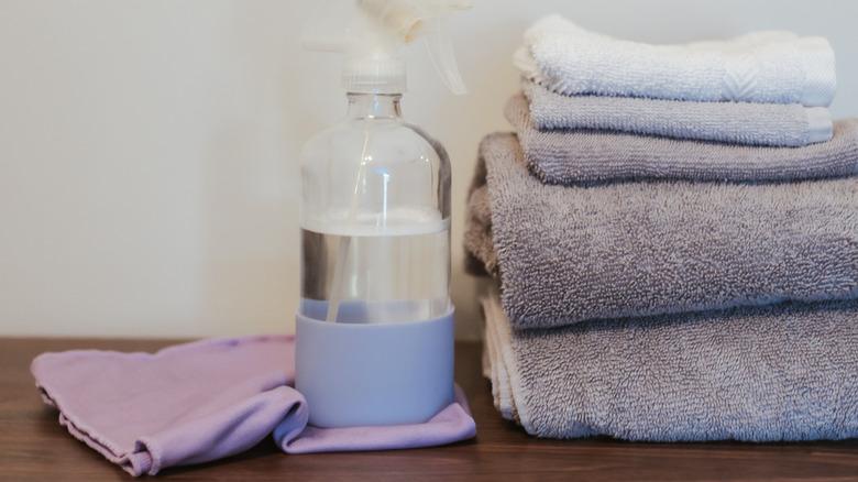 Cleaning rags and towels with a spray bottle containing clear liquid.