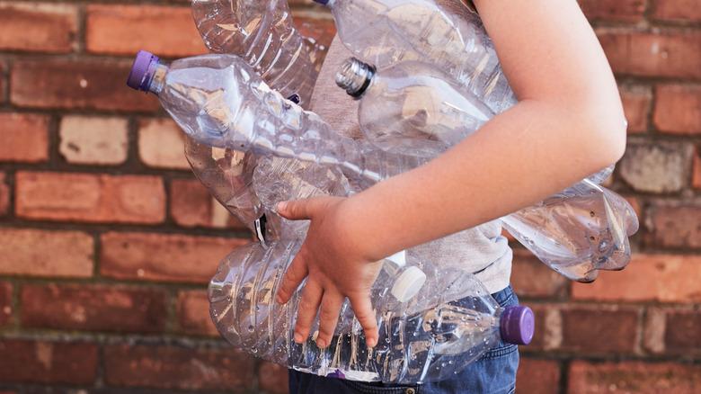 Woman holding used plastic water bottles