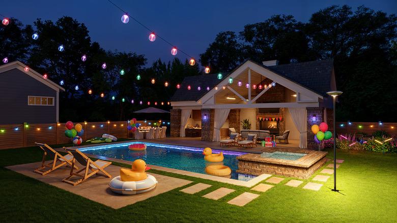 pool area with colorful Govee string lights above, garden lights, and post light creating the perfect lighting for an evening birthday party
