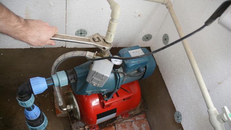 hand connecting a well pump to a home's water supply