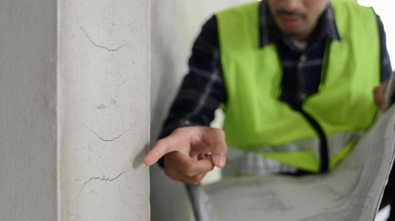 Inspector or appraiser pointing to cracks in a wall