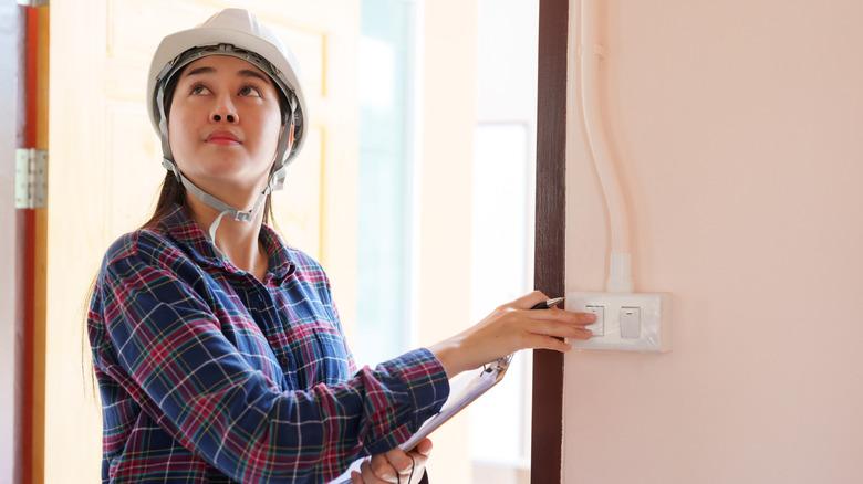 Inspector in safety gear testing a light switch