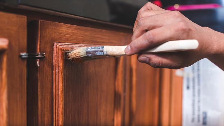 close up of hand painting wood kitchen cabinets
