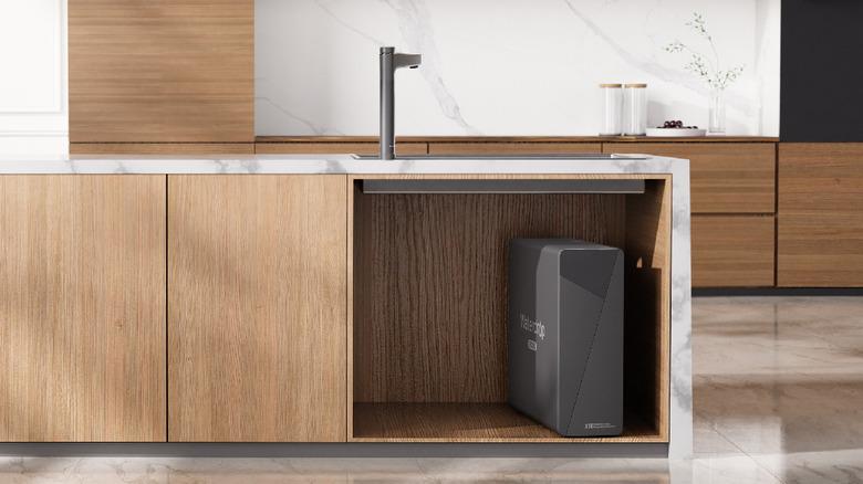 Waterdrop Filter X16 located in an open wooden cabinet under the sink in a kitchen