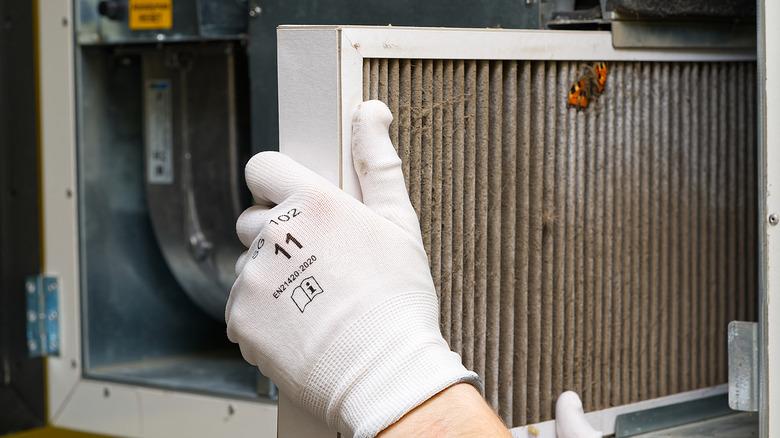 Hand replacing dirty HVAC air filter