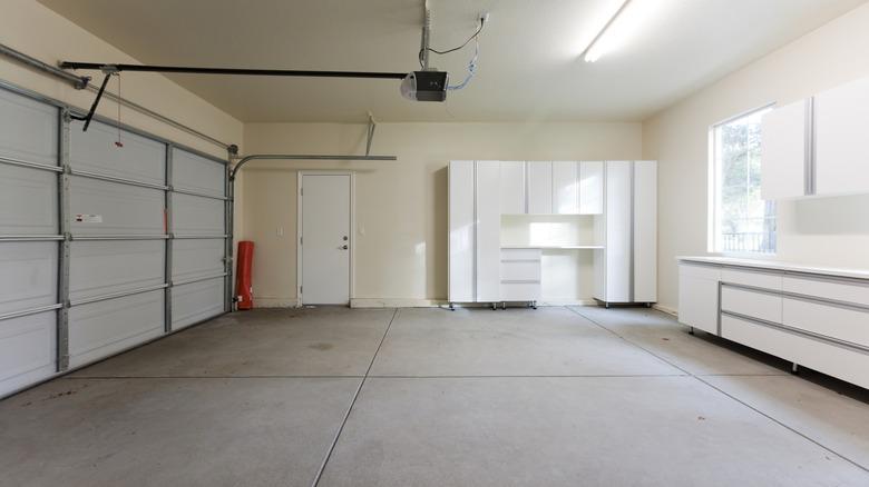 empty garage with white cabinets and shelves and concrete floor