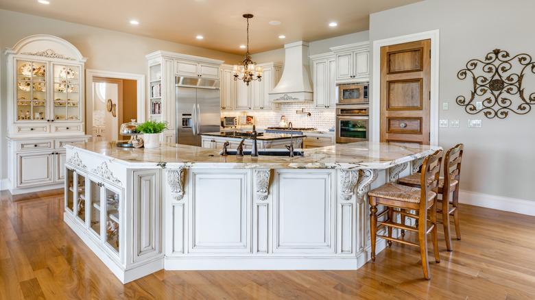 A well-lit French Country kitchen in white, beige, and wood tones