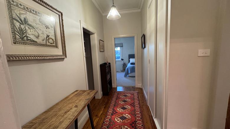 Home hallway with bench, bookshelf, and runner rug