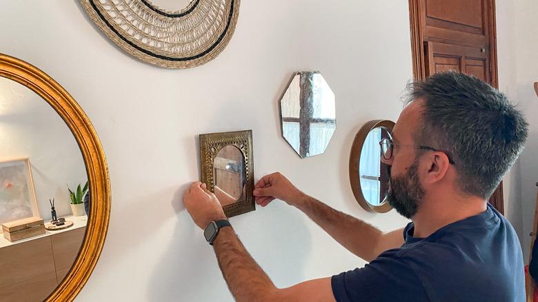 Man hanging mirrors in a home hallway