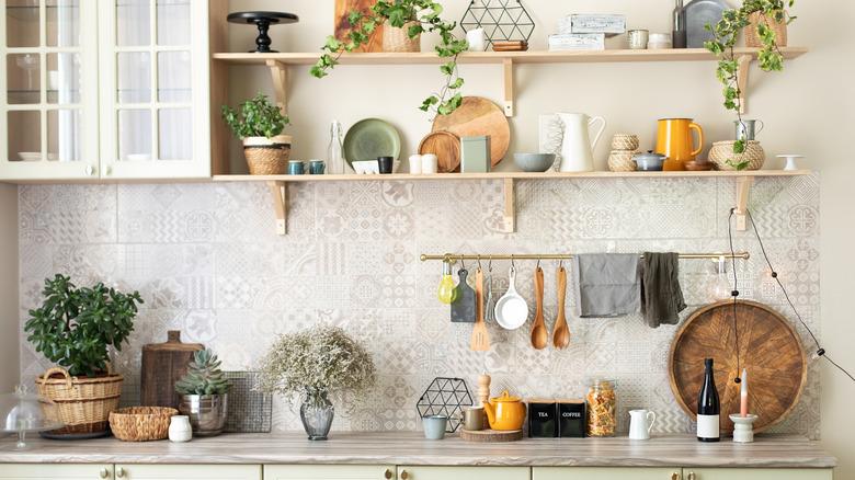 eclectic neutral kitchen with open upper shelving styled with plants and kitchenware in natural wood, white, green, and mustard tones