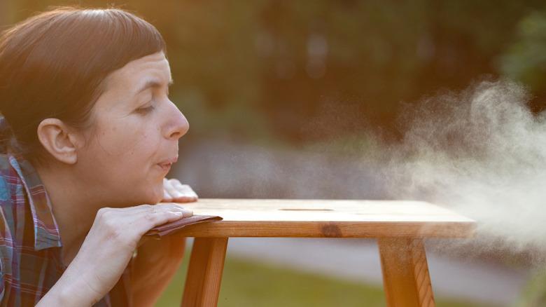 woman blowing off sanding dust