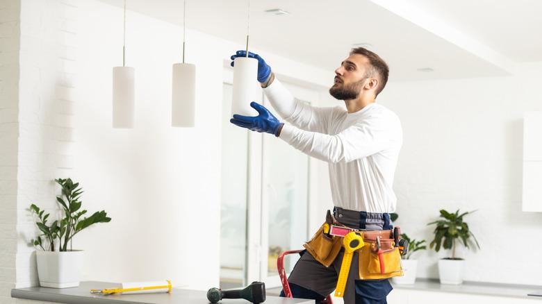 Man adjusting the height of kitchen pendant lights