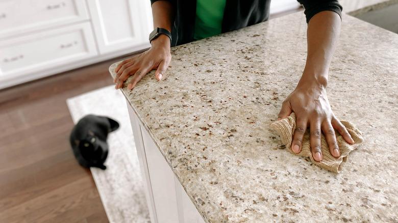 person wiping granite countertop