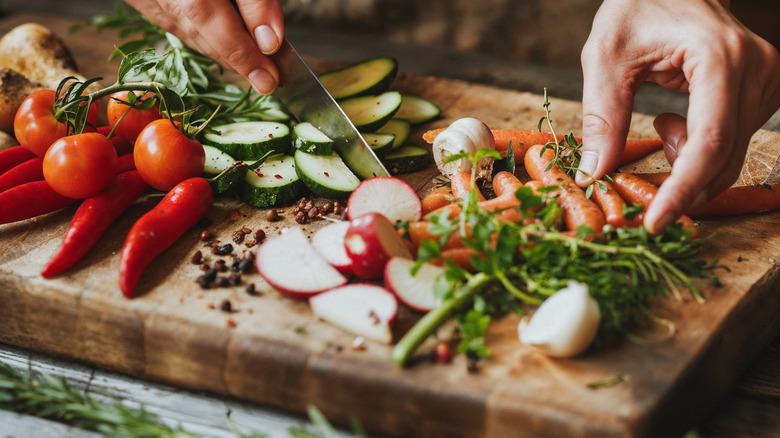 Hands chopping vegetables on chopping board
