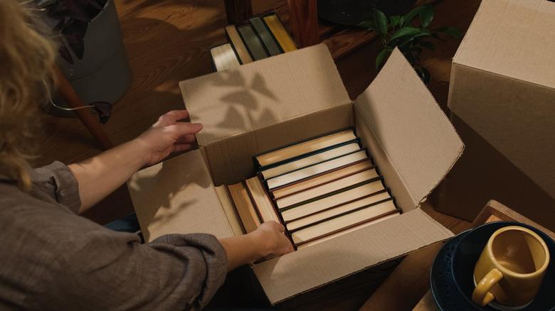 person packing box of books for moving