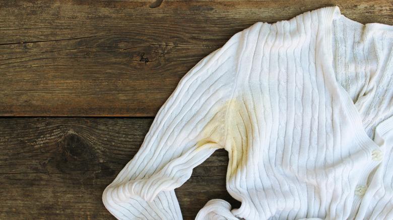 A yellow stain on the armpit of a white cardigan sweater.