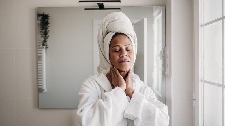 woman using bath towel in front of a mirror