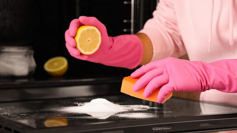 person cleaning stovetop with lemon and baking soda