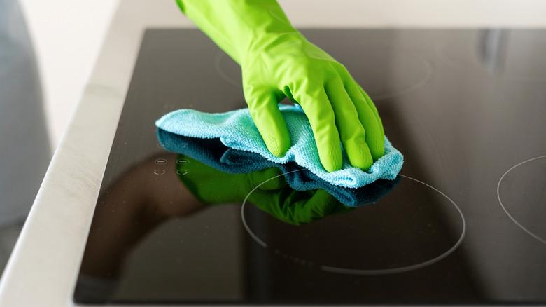 Hand cleaning glass stovetop with cloth