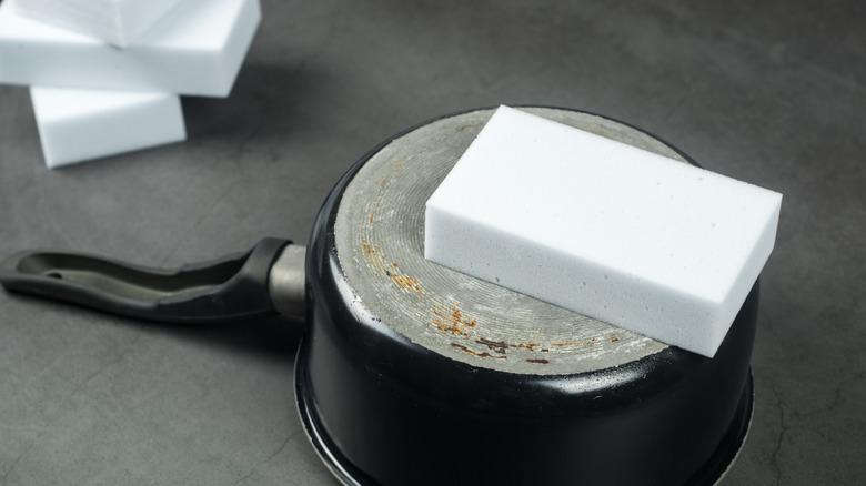 melamine foam sponge (or magic eraser) sitting on top of the underside of a cooking pot