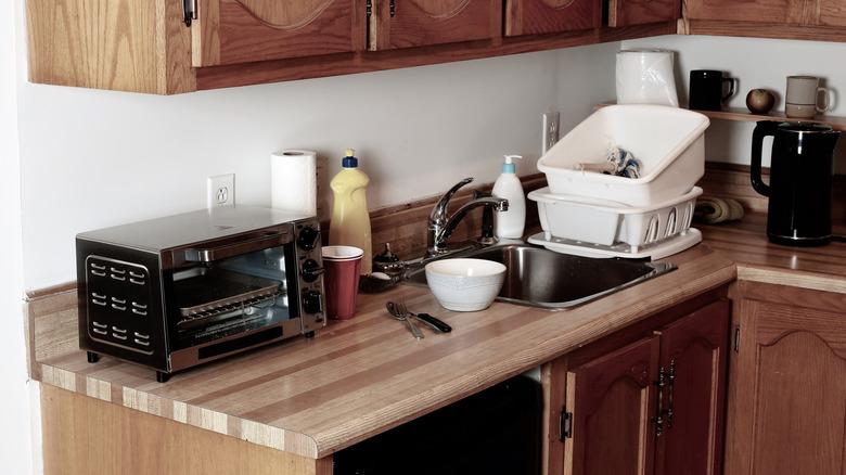 Wooden kitchen counter with utensils and clutter