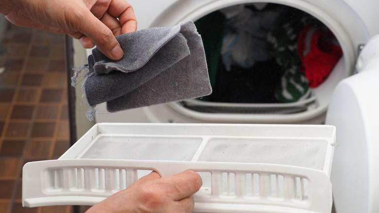 woman's hand removing lint from dryer trap