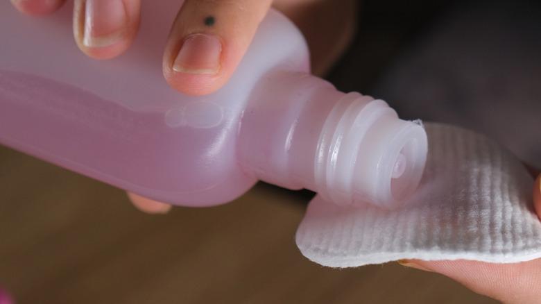 A bottle of acetone being poured onto a cotton swab.