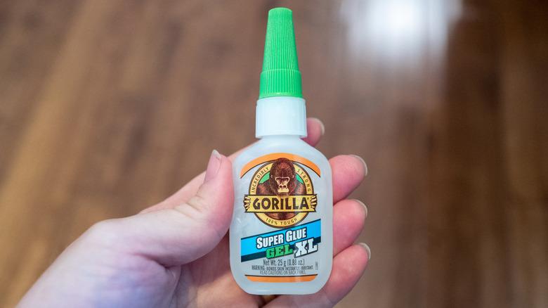 A close up of a hand holding Gorilla Glue.