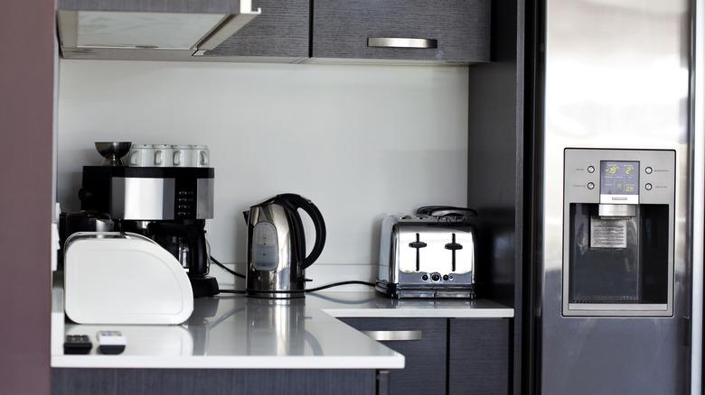 A sleek, modern kitchen with kitchen appliances on the countertop, including an electric kettle, coffee maker, and toaster.