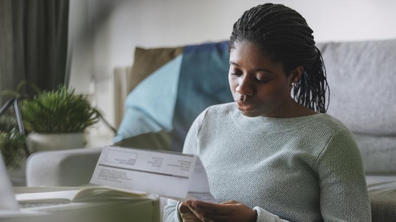 a woman sitting on the floor reading her electric bill