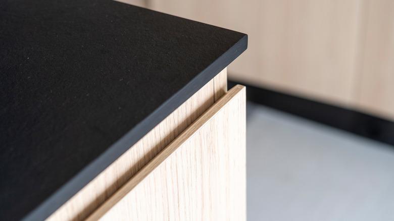 thin black kitchen countertop on wood cabinets
