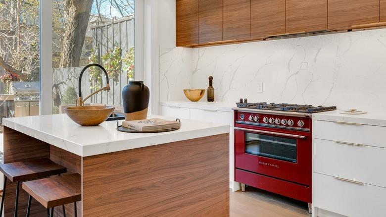 A kitchen with thick stone countertops and red oven