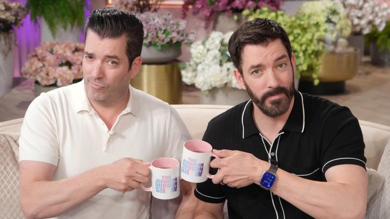 Jonathan and Drew Scott clinking coffee mugs