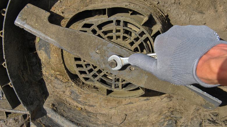 Hand replacing a dirty lawn mower blade