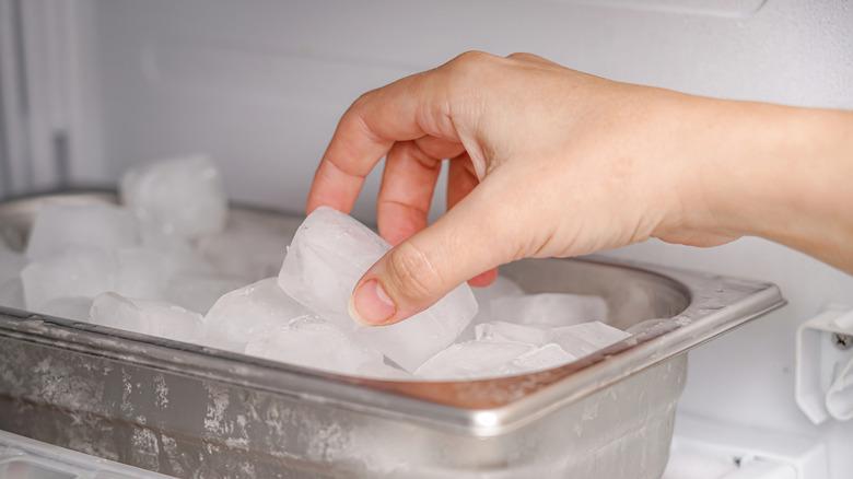 hand reaching for an ice cube in freezer