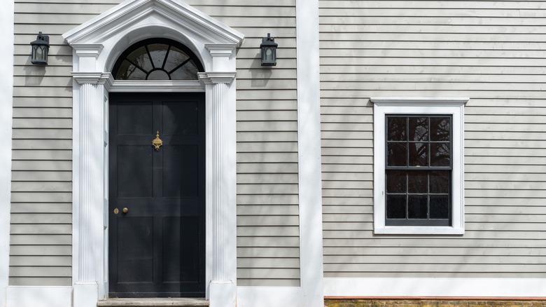 Gray home with black pedimented door.