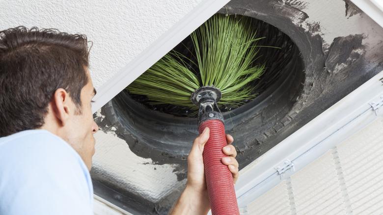 Man cleaning air duct in a home