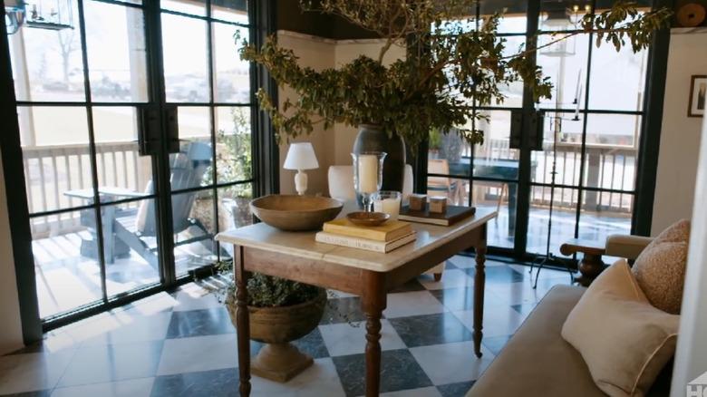 A sun-drenched living room with black-and-white marble checkered floors, designed by Nate Berkus and Jeremiah Brent