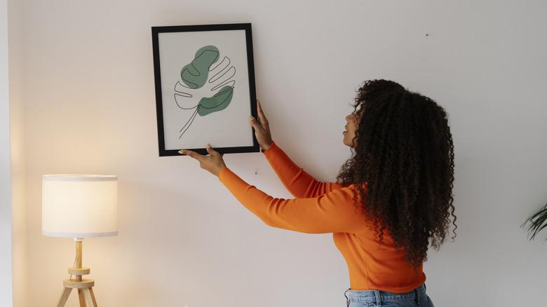 person hanging picture frame on wall