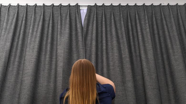 woman closing blackout curtains