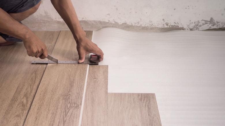 a technician is installing luxury plank vinyl flooring.